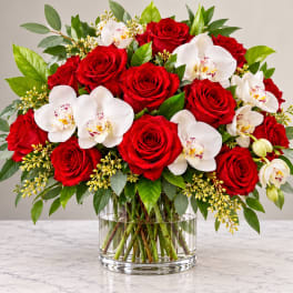 Red roses and white orchids in a clear glass vase