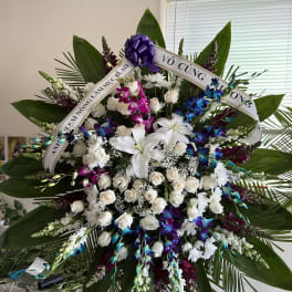 Large standing floral spray with white lilies, roses, and purple orchids