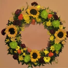 Circular floral wreath with sunflowers, roses, and mums