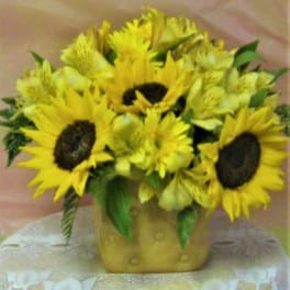 Bouquet of yellow sunflowers and alstroemeria in a gold vase