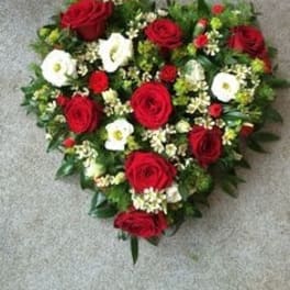 Heart-shaped bouquet of red and white flowers on a gray surface