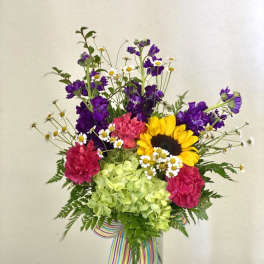 Colorful mixed bouquet in a clear glass vase with a striped ribbon
