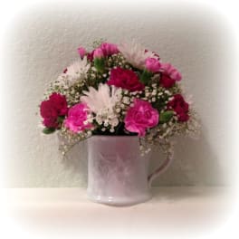 Pink and white flowers arranged in a lavender mug
