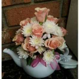 Pink and white flower arrangement in a white teapot