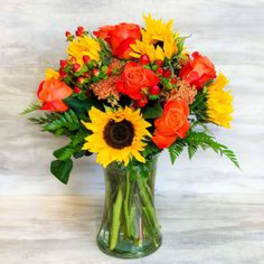 Bouquet of sunflowers and orange roses in a glass vase