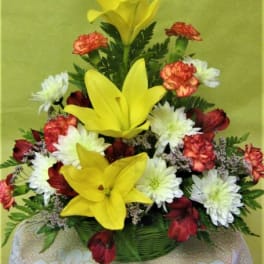 Yellow lilies with white and red mixed flowers in a basket arrangement