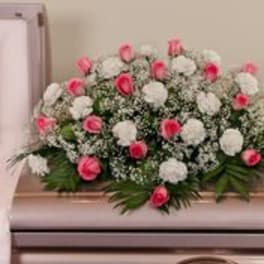 Pink and white floral casket spray with greenery
