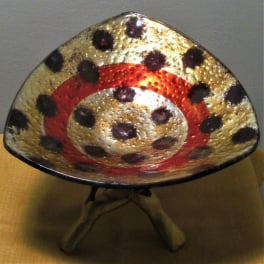 Decorative metallic bowl with red and black spotted pattern on a stand