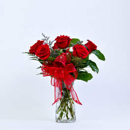 Red roses in a clear glass vase with a red ribbon bow