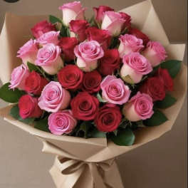 Large bouquet of red and pink roses wrapped in tan paper with a tied ribbon