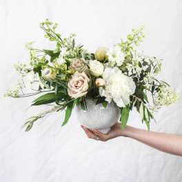 Low floral arrangement in a speckled ceramic bowl with white and blush blooms