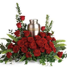 Red roses arranged around a silver urn with greenery