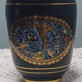 Black decorative urn with gold trim and a colorful emblem
