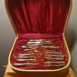 Open case holding a set of silver and gold flatware