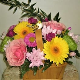 Basket arrangement with pink and yellow flowers and greenery