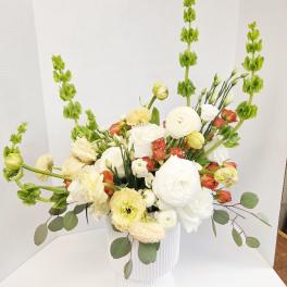 White and pale yellow floral arrangement in a ribbed white vase