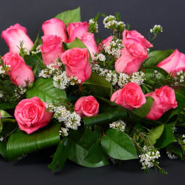 Pink roses arranged with small white filler flowers and greenery