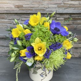 Bright yellow and purple mixed bouquet in a decorative vase