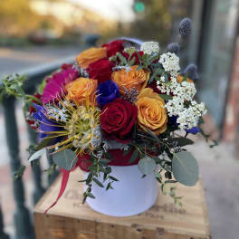 Mixed bouquet of roses and colorful blooms in a white hat box