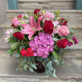 Pink lilies and red roses arranged with hydrangea in a vase