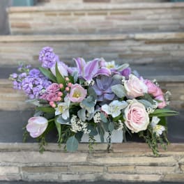 Pastel floral arrangement in a white container with pink roses and lilies