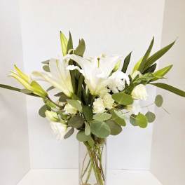 White lilies and roses in a tall glass vase