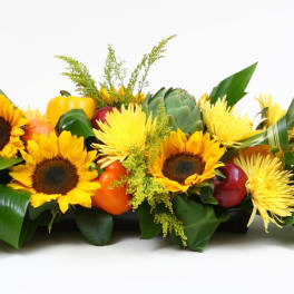 Low floral centerpiece with sunflowers and gourds in a rectangular container