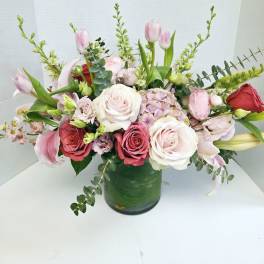 Mixed pink and white flowers arranged in a green glass vase