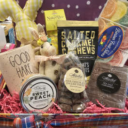 Gift basket with candy, a candle, a plush bunny, and a plaid ribbon