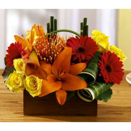 Orange and red floral arrangement with yellow roses in a wooden box