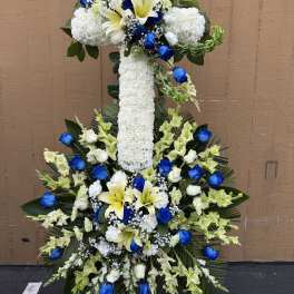 Large white floral cross with blue roses and yellow lilies