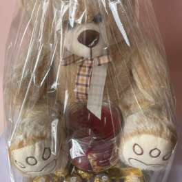 Teddy bear gift basket wrapped in clear plastic with a red bow