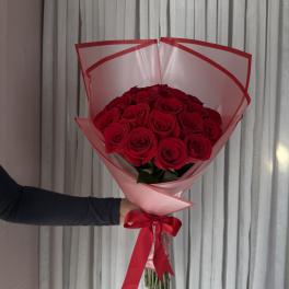 Bouquet of red roses wrapped in pink paper with a red ribbon