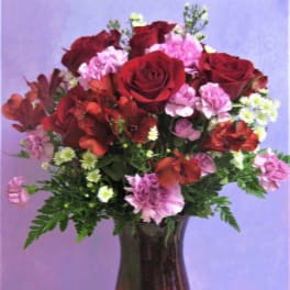 Red roses and pink carnations in a dark glass vase