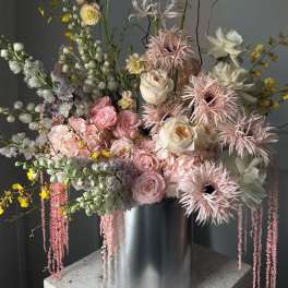 Tall pastel floral arrangement in a silver cylinder vase