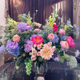 Large mixed bouquet in a metallic vase with pink, purple, and yellow blooms