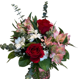 Bouquet of red roses, pink alstroemeria, and white daisies in a glass vase