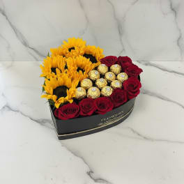 Heart-shaped box with red roses, sunflowers, and gold chocolates