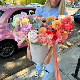 Large mixed bouquet in a gray hatbox held by a woman