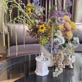 Large mixed floral arrangement in a white vase with cascading blooms