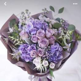 Lavender and purple bouquet of roses and hydrangeas wrapped in mauve paper