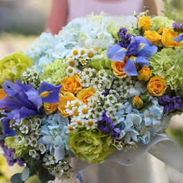 Colorful bouquet with blue hydrangeas, yellow roses, and purple irises