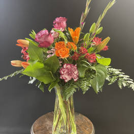 Mixed bouquet of orange and pink flowers in a clear glass vase