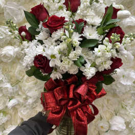 Red roses and white daisies in a bouquet with a red ribbon