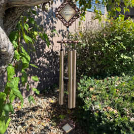 Decorative wind chime hanging from a tree in a garden