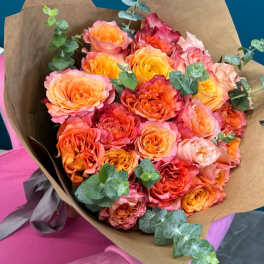 Bouquet of orange and pink roses wrapped in brown paper