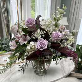 Lavender roses in a glass vase with white filler flowers