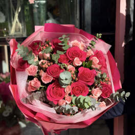 Bouquet of hot pink and blush roses wrapped in pink paper