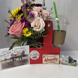 Mixed bouquet with pink and white roses in a jar, beside gift cards and a drink cup.