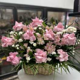 Pink roses and white filler flowers in a wicker basket